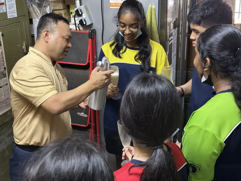 Students on a real-world learning visit, observing and discussing design challenges with a facilitator as part of design thinking workshop