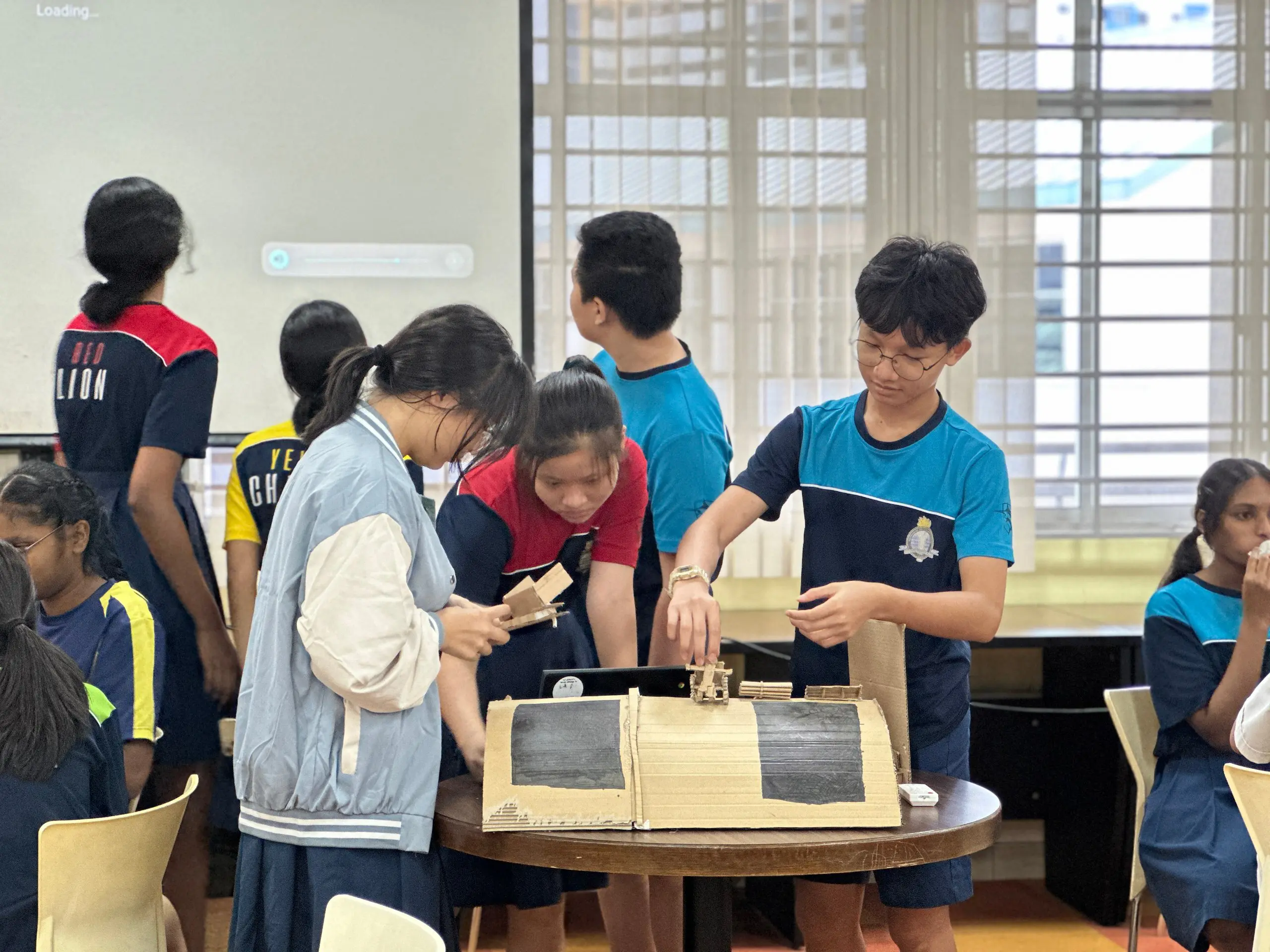 Singapore secondary school students building a cardboard prototype model during a design thinking workshop